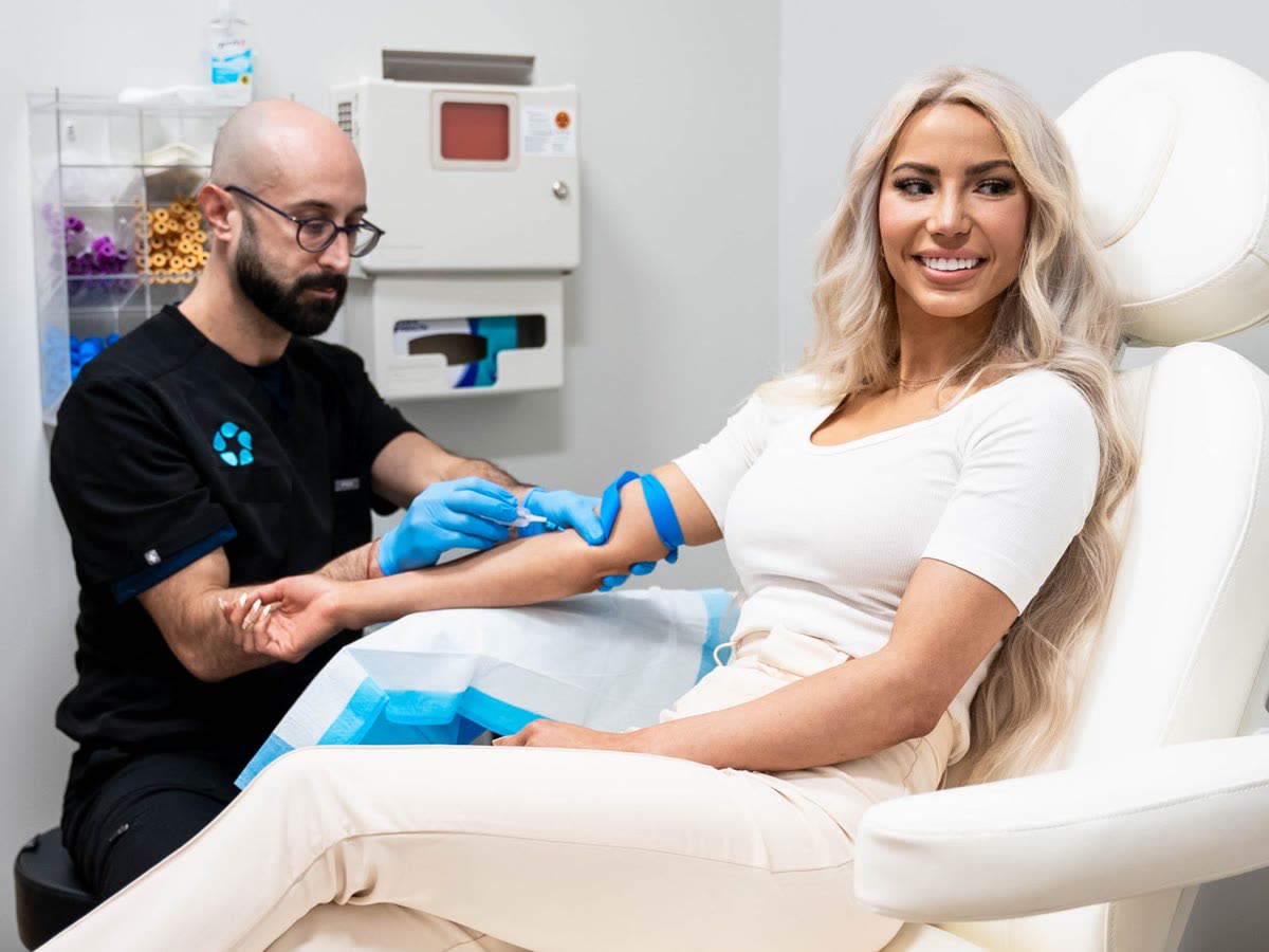 A smiling patient has her blood drawn by a Relive Health clinician